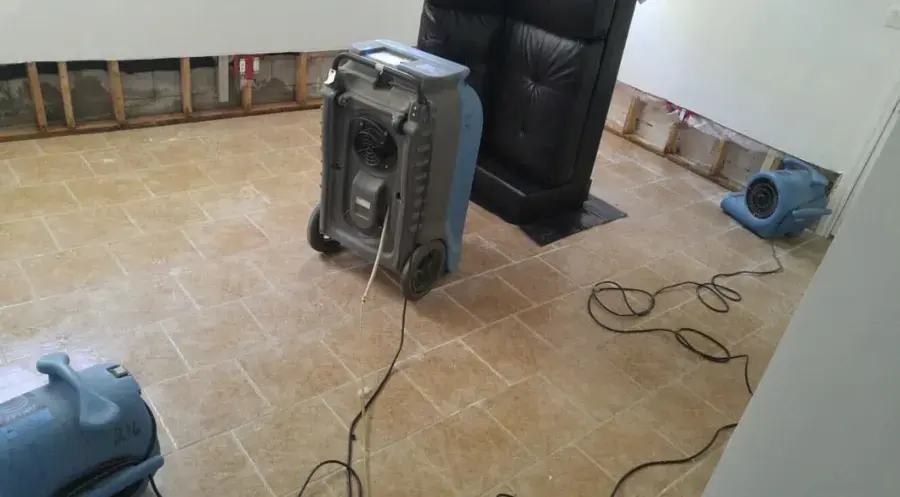 Dehumidifier and air movers on a tiled floor with the lower walls opened during water damage drying in a Coatesville, PA home