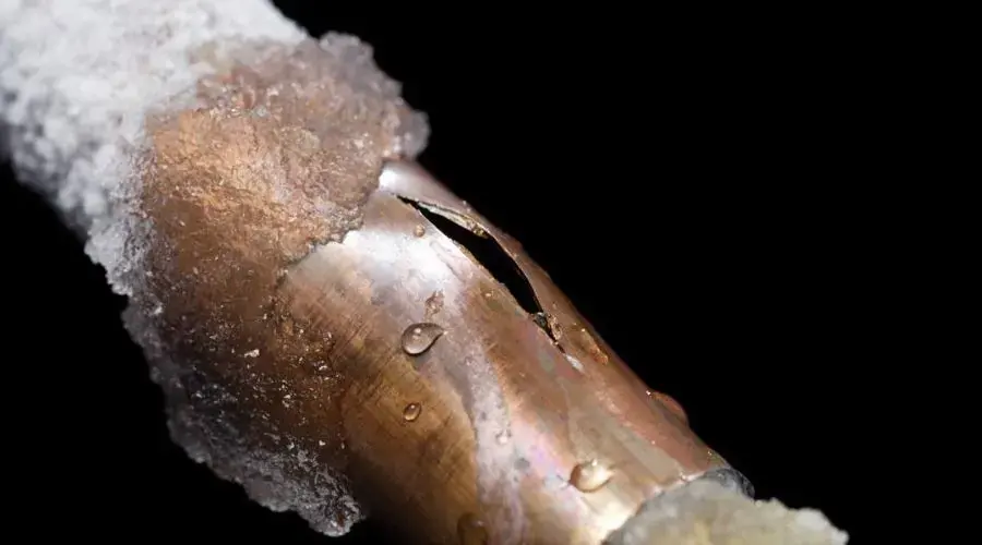 Burst pipe water damage in Downingtown, PA: a copper water pipe split open along its side