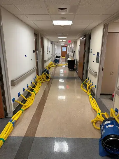 Commercial water damage in Downingtown, PA: drying hoses and air movers lining a building hallway