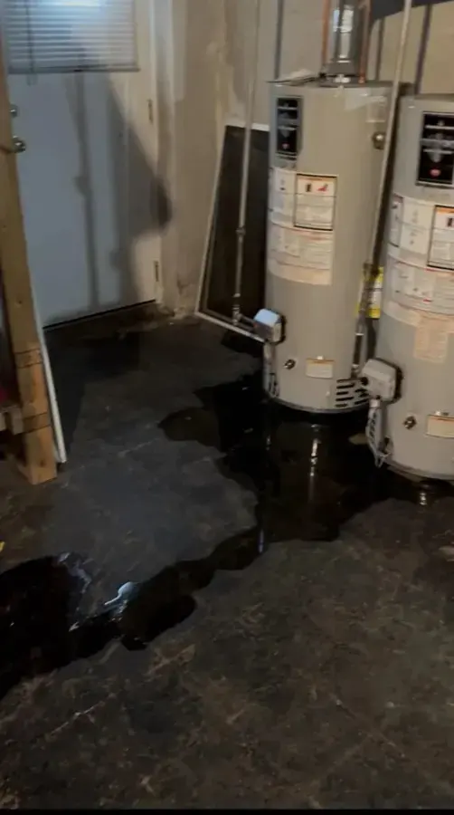 Water heater leak cleanup in Downingtown, PA: water pooled on a basement floor around two water heaters